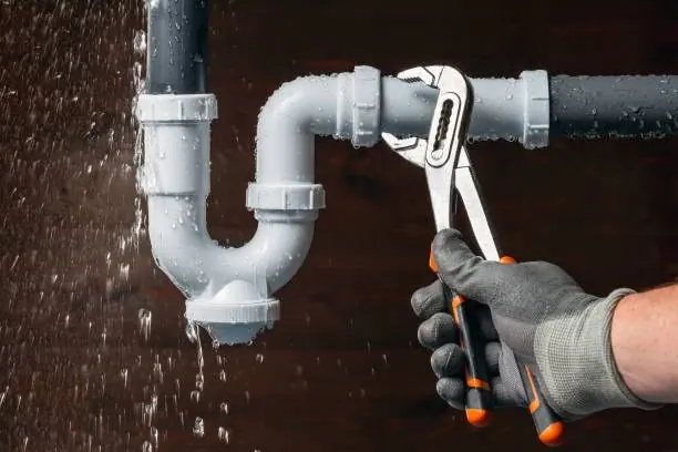 Plumber tightening a drain pipe with pliers